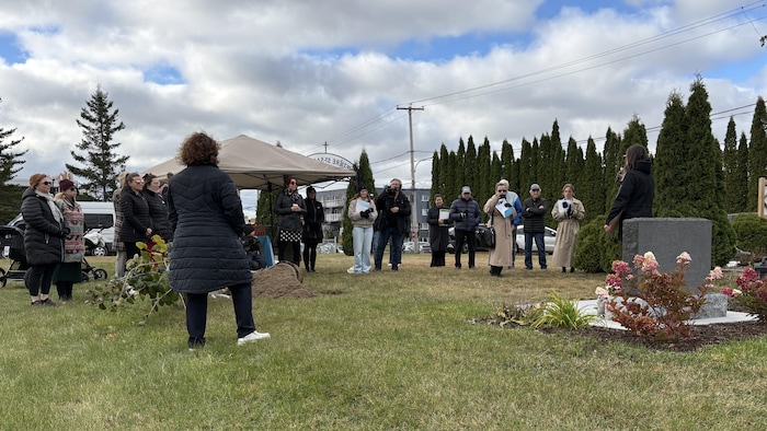 Des gens sont réunis dans un cimetière.