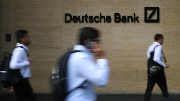 It was hoped that disruption in the banking sector had been nipped in the bud, but shares in the German titan plunged 14 per cent at one point on Friday morning. Three men walk in front of a wall on which we see the logo of the Deutche bank.