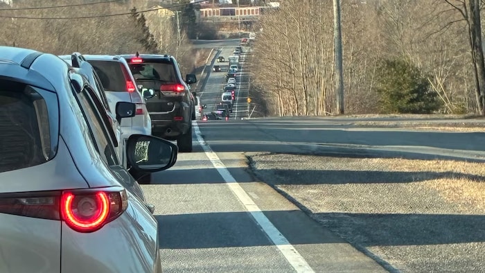 Une longue file de voitures immobiles sur une route de campagne.