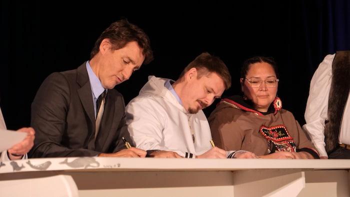 Le premier ministre du Canada, Justin Trudeau, le premier ministre du Nunavut, P.J. Akeeagok, et la présidente de Nunavut Tunngavik Inc. (NTI), Aluki Kotierk en train de signer la dévolution, le 18 janvier 2024.