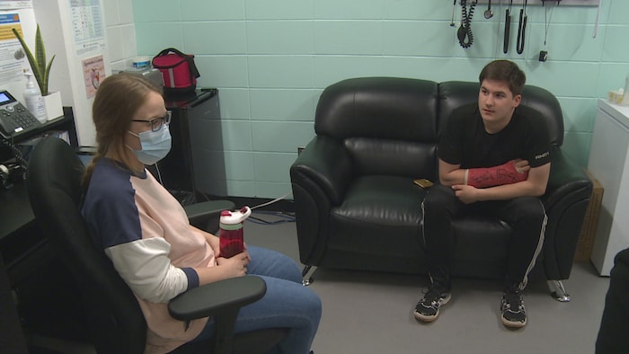 Un jeune assis sur une causeuse discute avec une infirmière dans son bureau, à l'Aire ouverte de Sept-Îles.