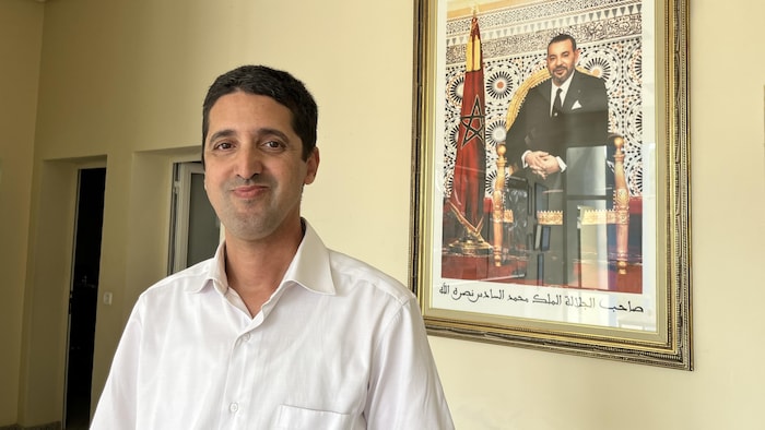 Abdellah Saphar à côté d'un portrait encadré du roi Mohammed VI.