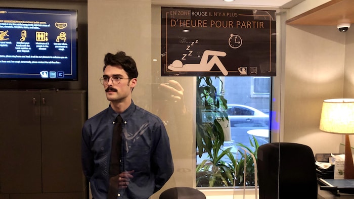 Un homme debout dans son bureau derrière une vitre.