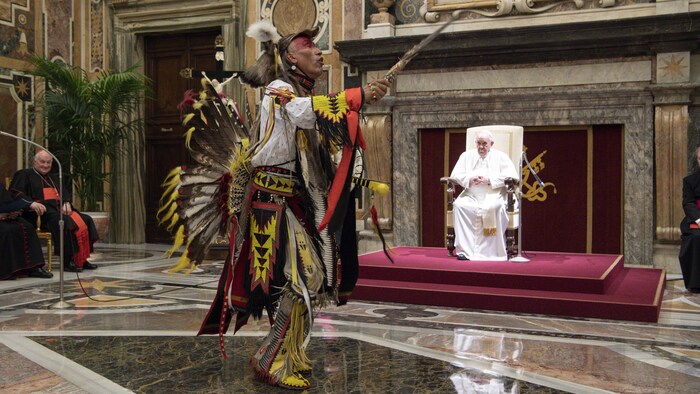أحد أفراد سكان كندا الأصليين يؤدي رقصة أمام أنظار البابا فرنسيس الجالس على كرسيه.