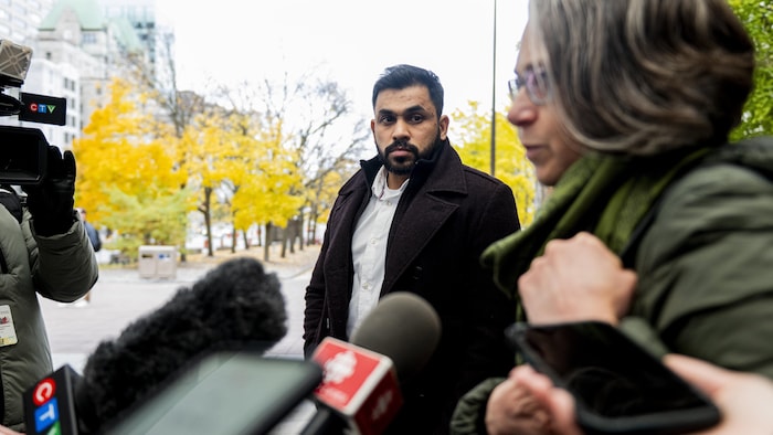 Dhanushka Wickramasinghe regarde lad avocate, Ronalee Carey, lorsqu'elle parle aux médias.