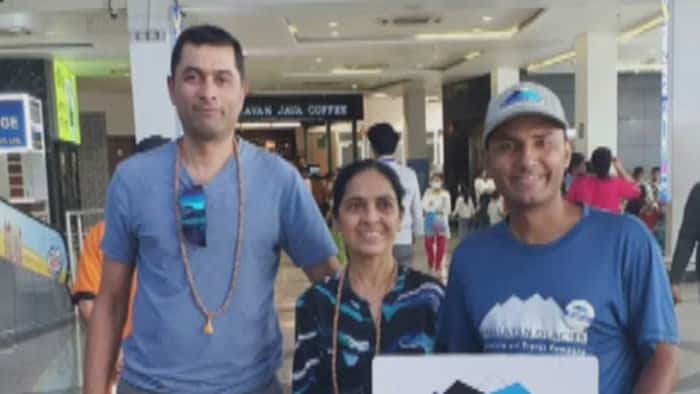 Dhaval Shah et Megha Shah sourient aux côtés d'un guide dans un aéroport.