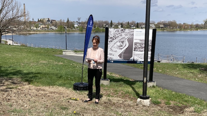 Diane Dallaire fait un discours devant un panneau historique au bord du lac Osisko.