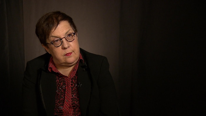 Mme Pacom est installée dans une pièce sombre dans le cadre d'une entrevue.