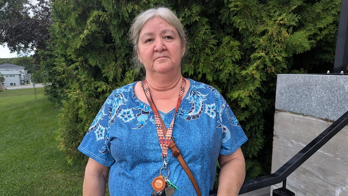 Diane Polson pose devant un cèdre devant le palais de justice de Ville-Marie, sans sourire.