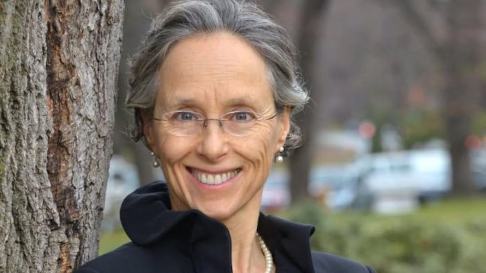 Dianne Saxe sourit à côté d'un arbre.