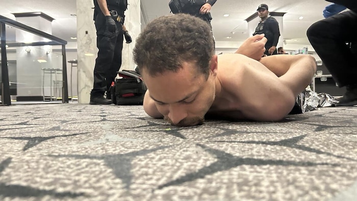 Un homme menotté est couché sur le ventre. 