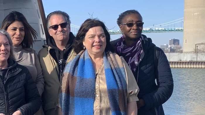 Un portrait de Gisèle Dionne entourée d'autres personnes.