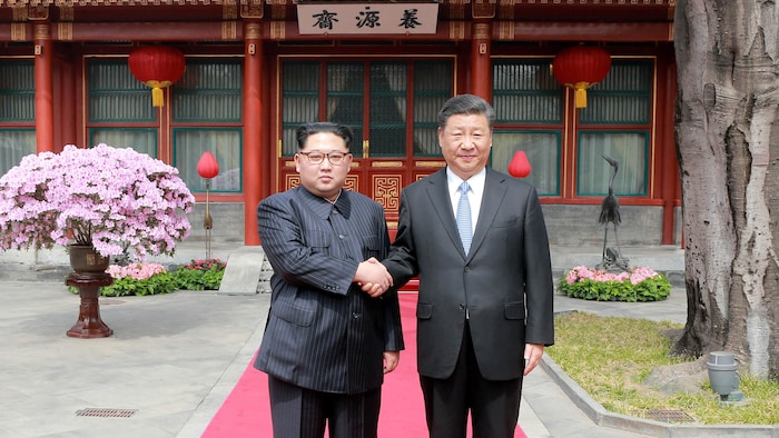 Kim Jong-un and Xi Jinping shake hands. 