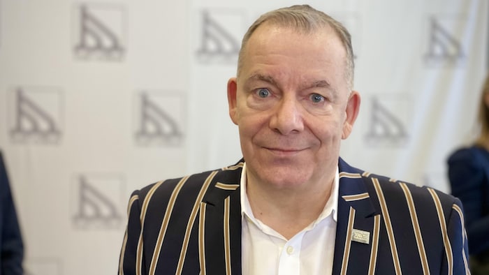 François Vaillancourt devant une pancarte de la ville.