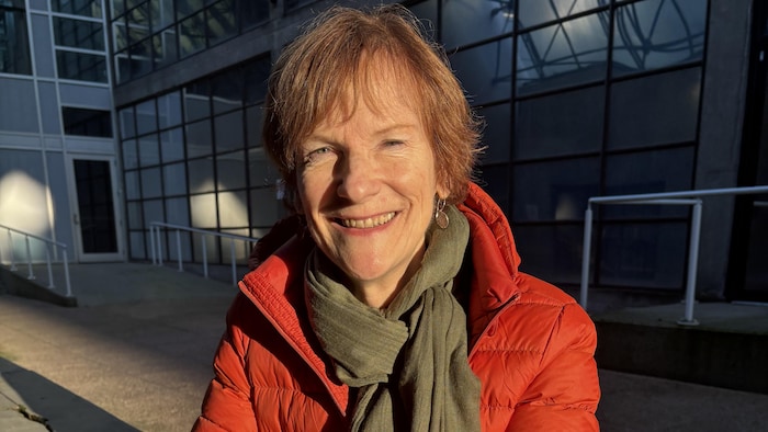 Une femme assise à une table en bois en extérieur.