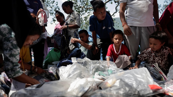 Des femmes et des enfants sont penchés sur des sacs en plastique dans lesquels se trouvent des vêtements.