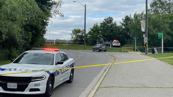 Une voiture de police derrière un ruban policier.