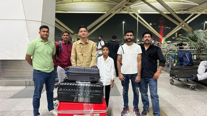 Un jeune homme avec des bagages à l'aéroport, entouré par d'autres personnes.