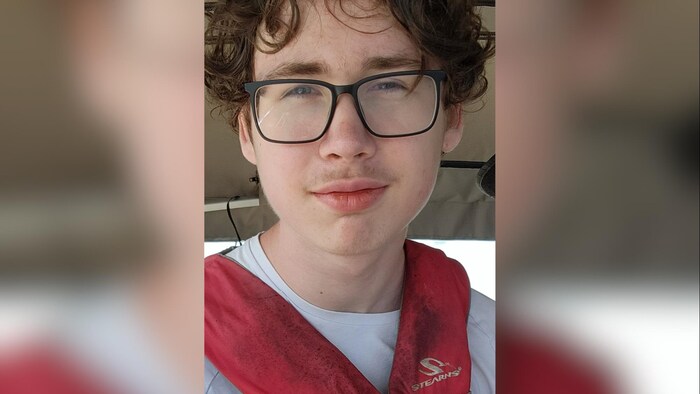 Niko Cadotte porte des lunettes, une moustache et une veste de flottaison.