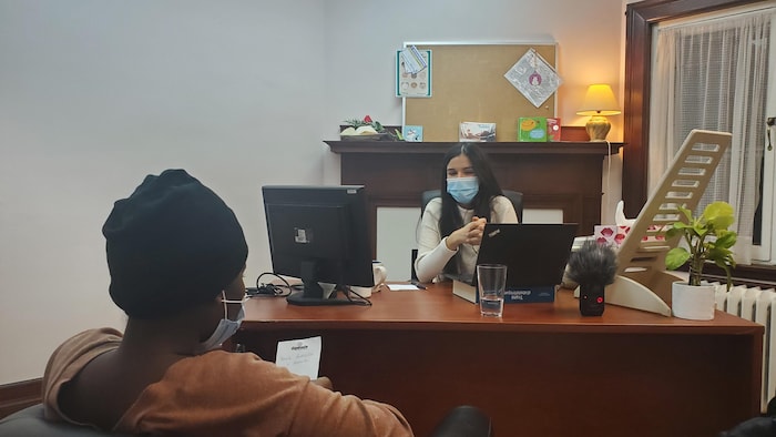 Une femme à un bureau discute avec une autre femme assise devant elle.