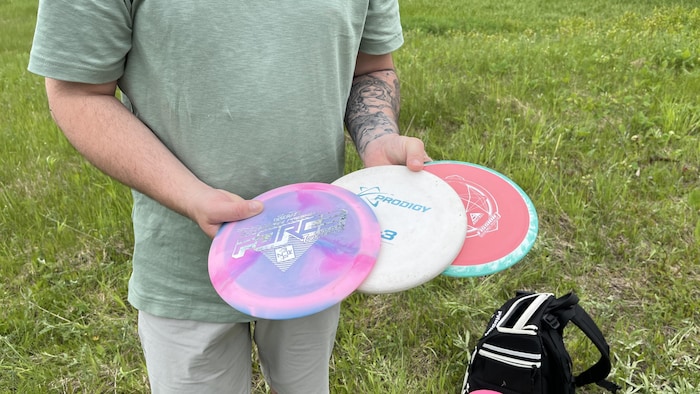 Un homme tient en main des frisbees.