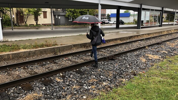 Une femme traverse un chemin de fer.