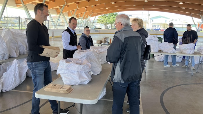 Trois personnes, debout derrière une table, échangent avec un homme et une dame.