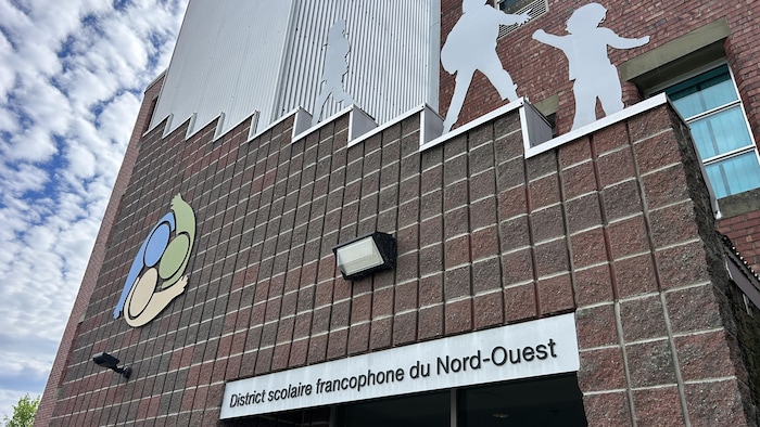 Un bâtiment en briques avec une enseigne où il est écrit « District scolaire francophone du Nord-Ouest».