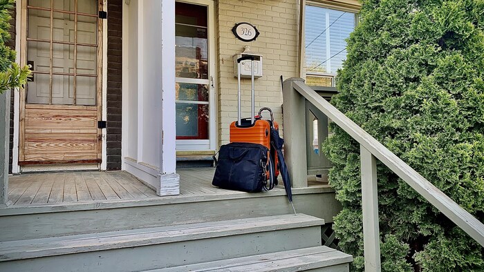 Une valise, un parapluie et un sac sur le proche d'une maison.