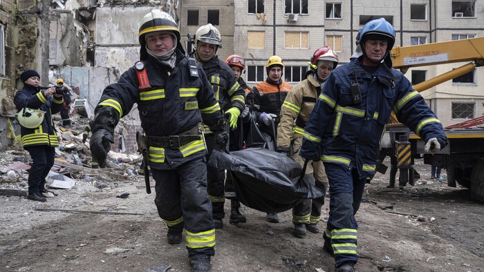 رجال الإنقاذ يحملون جثة رجل قُتل في القصف الصاروخي على مبنى سكني في دنيبرو في 14 كانون الثاني / يناير 2023.