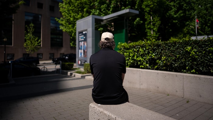 Un homme, dont l'identité est protégée, est assis de dos dans la rue à Vancouver, en Colombie-Britannique, le jeudi 7 mai 2026.