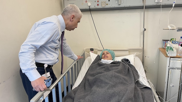 Un médecin penché sur une patiente sur un lit d'hôpital.