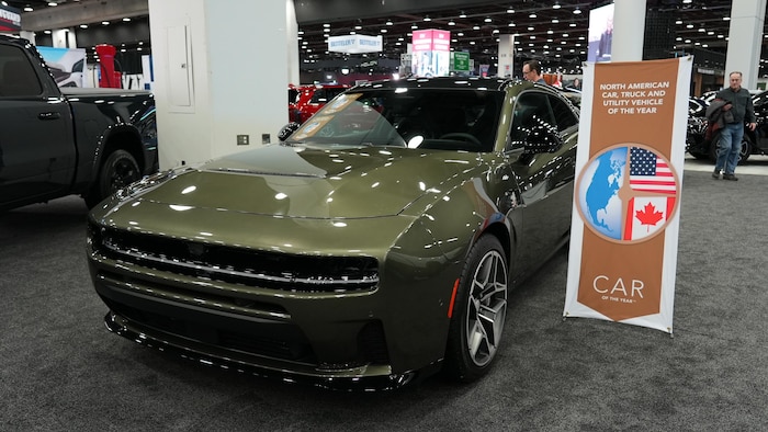 Une Dodge Charger neuve, scintillante, présentée à côté d’une banderole qui annonce son titre de voiture de l’année.