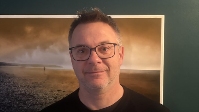 Dominic Boula, un gomme avec des cheveux courts et des lunettes, regarde l'objectif.