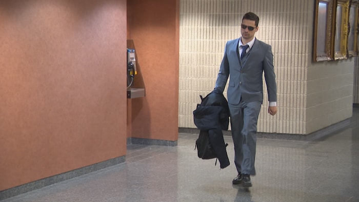 Un homme en lunettes fumées dans un couloir du palais de justice de Montréal.