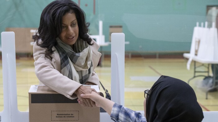 Dominique Anglade serre la main d'une employée électorale.
