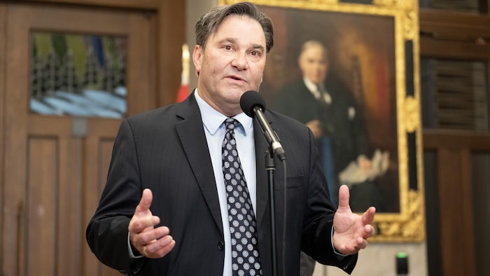 Don Davies parle debout devant un micro.