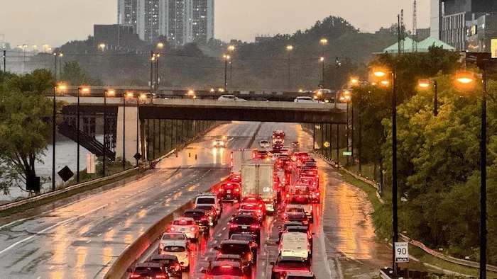 Des véhicules immobilisés sur une autoroute à cause d'une immense flaque d'eau sous un viaduc. 