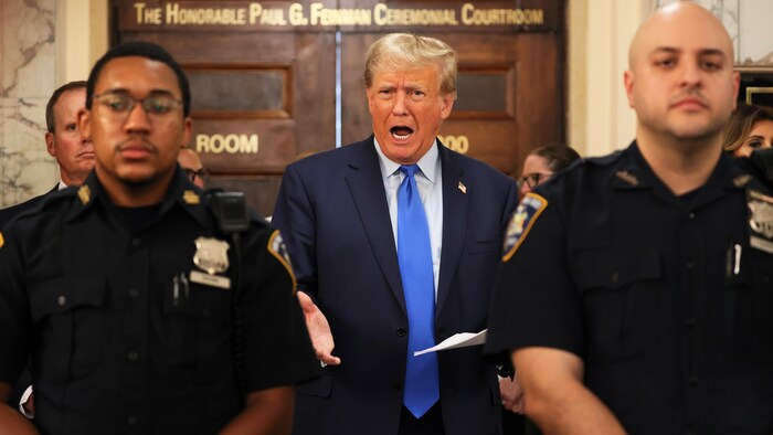 Donald Trump derrière deux policiers.