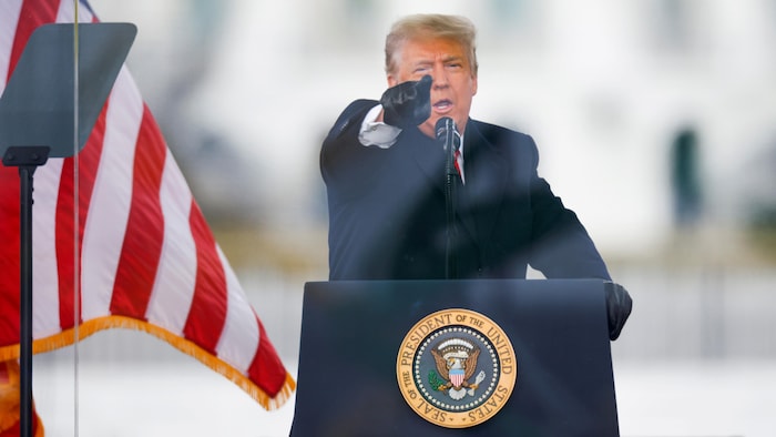 Devant un micro, Donald Trump pointe son doigt devant lui.