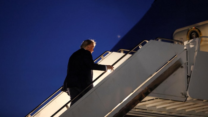 Donald Trump monte les marches menant à l'avion Air Force One à la tombée de la nuit.