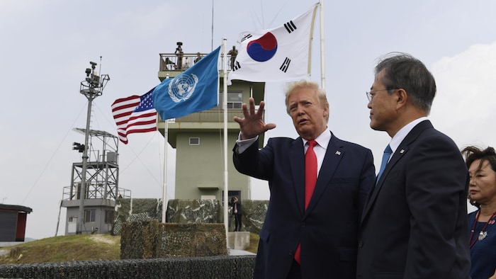 Trump et Moon Jae-in, le vent dans les cheveux, observent au loin depuis une plateforme surélevée.