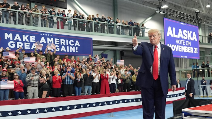 Donald Trump montre un pouce en l'air devant une foule et des pancartes électorales, le 13 octobre 2026 à Wasilla, en Alaska.