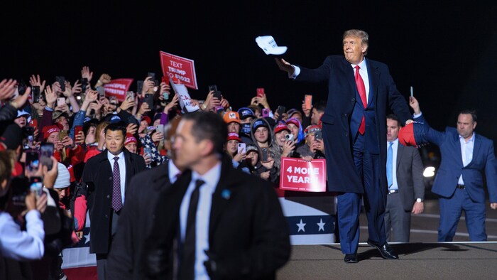 Donald Trump lance une casquette dans une foule.