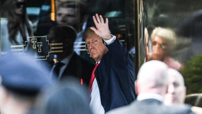 Former President Donald Trump waves to the crowd and cameras outside the entrance to Trump Tower.