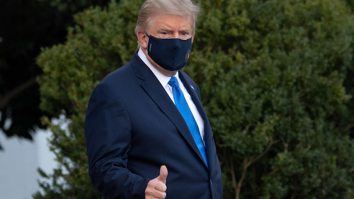 L'air fatigué et portant un masque, Donald Trump lève son pouce en l'air pour la presse.