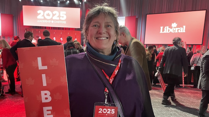 Une femme pose avec une pancarte du Parti libéral.