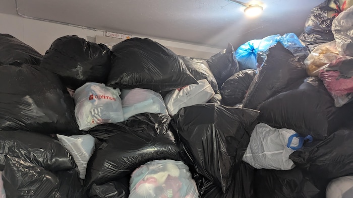 Des sacs de poubelles sont empilés les uns sur les autres dans une pièce.