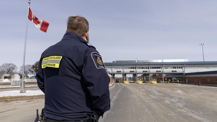 A border service agent of Canada, from back, observes vehicles entering Canada. carney promised significant changes canada's