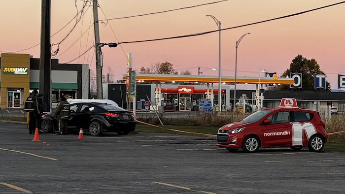 Des policiers inspectent un véhicule dans un stationnement.